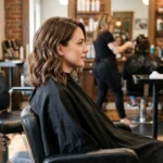 Woman with classic wavy lob haircut at collarbone length showing soft natural waves in salon chair