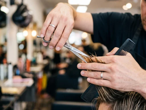 Professional hairstylist's hands cutting curtain bangs with precise scissor technique in bright salon lighting