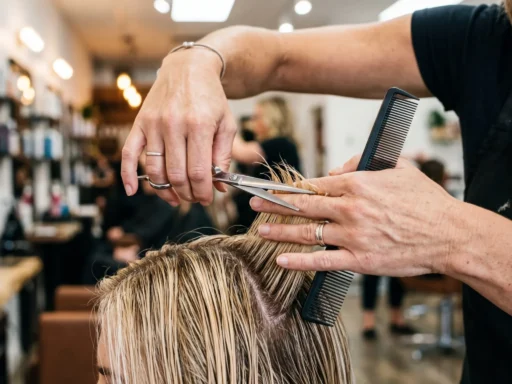 Professional hairstylist hands cutting curtain bangs with scissors and comb in bright salon lighting